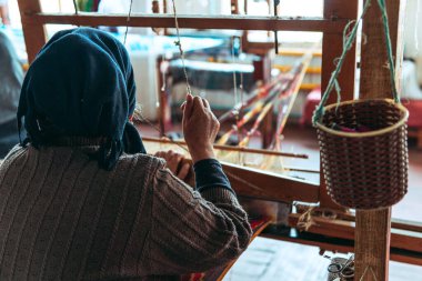 Geleneksel pedal dokuma tezgahında kumaş ören kadın