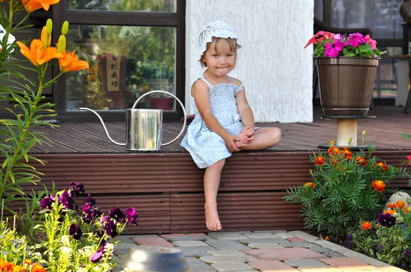 Little girl sitting on the porch with a watering can Stock Image