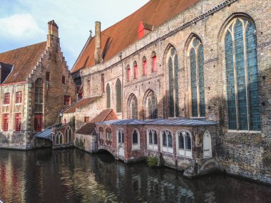The historical city center of Bruges with medieval brick architecture reflected in water of a canal 