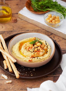 Ekmek çubuklu ev yapımı humus ve tahta arka planda maydanoz kopyalama alanı. Seçici odaklanma. Orta Doğu vejetaryen mezesi, lezzetli aperatif, aperatif ya da yayılmış. Vejetaryen gıda konsepti.