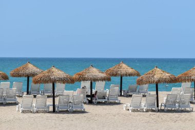 Ekvador 'da bir tatil köyünün plajında saman şemsiyeler.