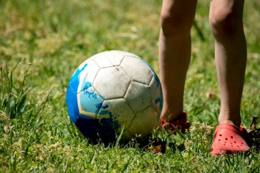 Beyaz ve mavi top çimlerin üzerinde. Futbol mu? Oyun oynayan çocuklar