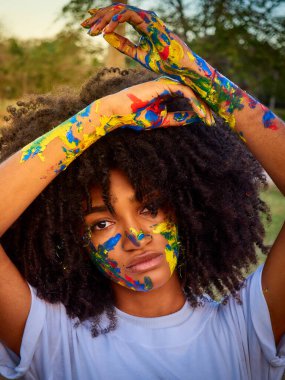 Yüzü farklı renklere boyanmış küçük kız doğanın tadını çıkarıyor.       