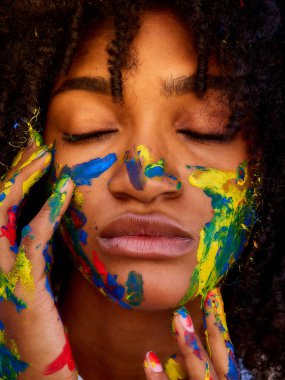 Yüzü farklı renklere boyanmış küçük kız doğanın tadını çıkarıyor.       