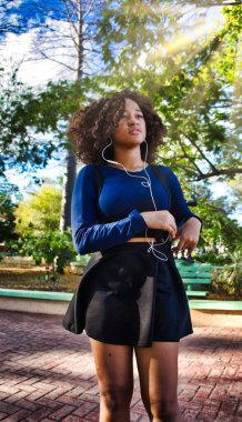 Kız cep telefonuyla parka gider, fotoğraf çeker ve müzik dinler..