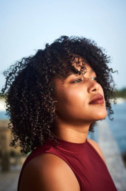 Gün batımında şehirde poz veren güzel bir genç kadının portresi.