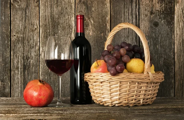 Ακόμα-ζωή. μπουκάλι κόκκινο κρασί, γυαλί και καλάθι με φρούτα — Φωτογραφία Αρχείου
