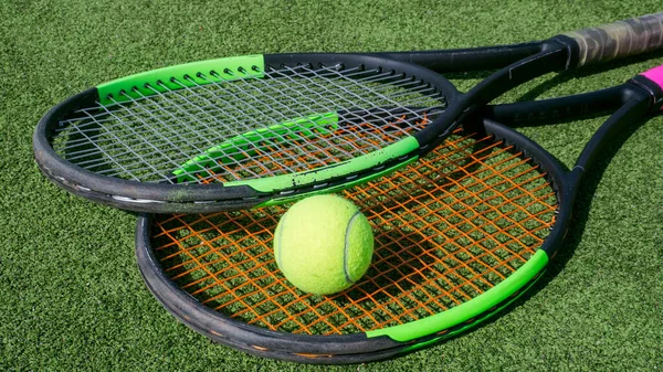Tenis topu ve raket yeşil sahada yatıyor. Yaklaş..