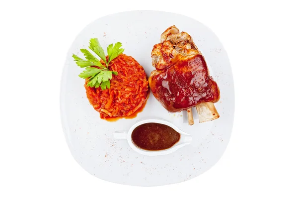 Grilled meat ribs on white plate with tomatoes chives and dark hot sauce — Stock Photo, Image