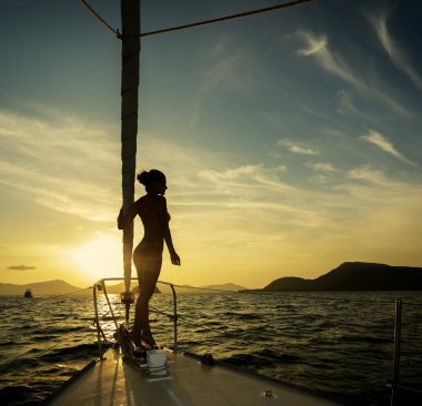 Kız bir yatta gün batımında ayakta