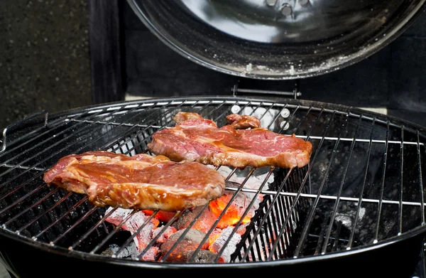 Hovězí steak na grilu s plamenama. — Stock fotografie