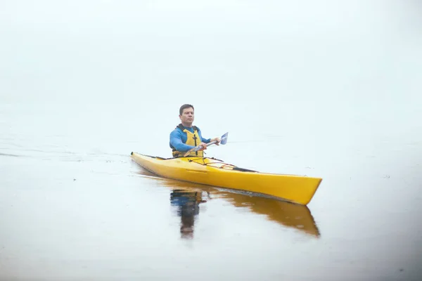 秋の霧の川でカヤックを漕いでいる男がいる — ストック写真