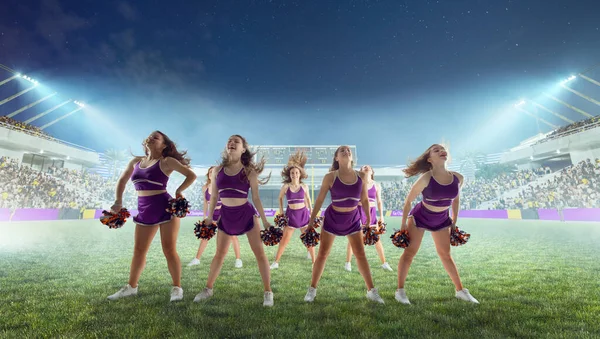 Group of cheerleaders in action on  stadium in night