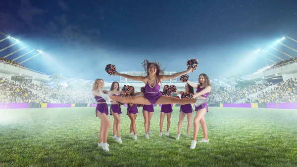 Group of cheerleaders in action on  stadium in night