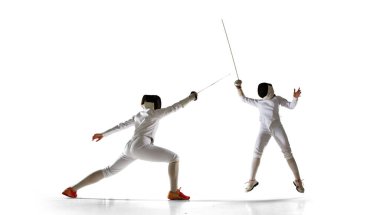 İki kadın eskrim sporcusu beyazlar üzerinde dövüşüyor.