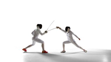 İki kadın eskrim sporcusu beyazlar üzerinde dövüşüyor.