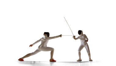 İki kadın eskrim sporcusu beyazlar üzerinde dövüşüyor.