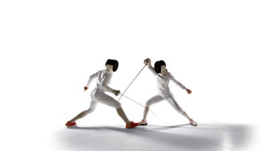 İki kadın eskrim sporcusu beyazlar üzerinde dövüşüyor.