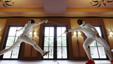 Eski eskrim salonunda iki kadın eskrim sporcusu kavga ediyor.