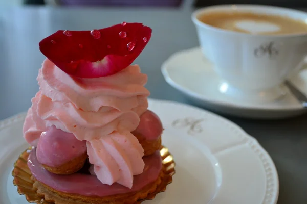 Dessert pastry eclairs, cream, jellied rose petal and cup and saucer