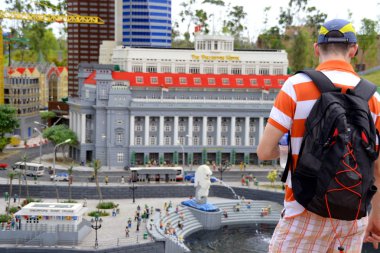 Tourist checking out model of Singapore at Legoland Malaysia clipart