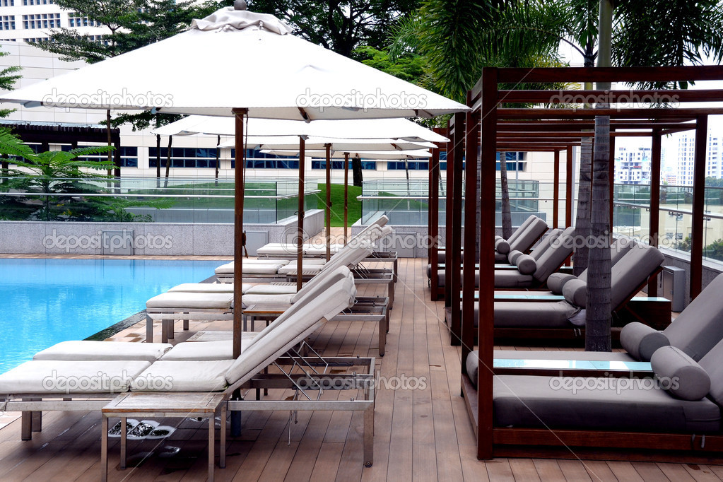 Lounge chairs and cabanas by swimming pool in condominium high-rise building