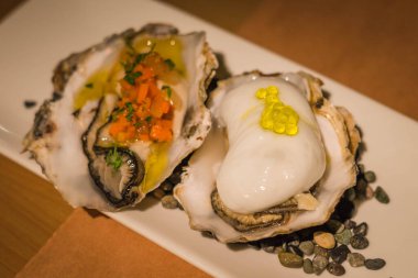 Beyaz porselen tabakta servis edilen bir çift çiğ Galiçya istiridyesi.