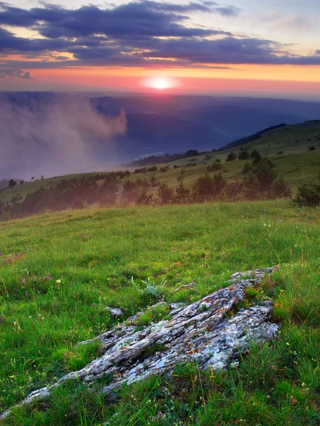 Prado verde e colinas durante o pôr-do-sol — Fotografia de Stock