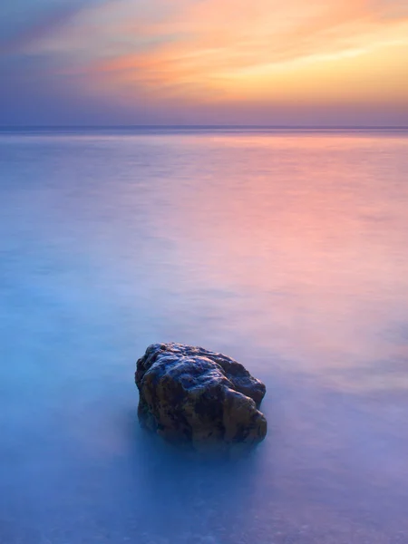 Pôr do sol no mar com pedra — Fotografia de Stock