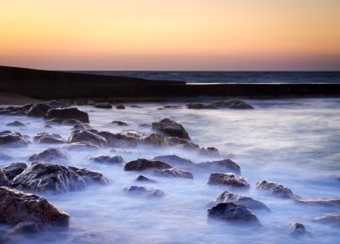 gün batımı sırasında su yansımaları ile deniz kıyısı.