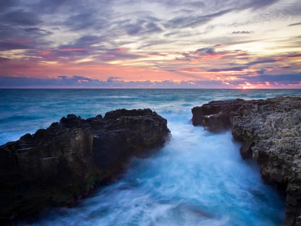 Costa con reflejos en el agua al atardecer . — Foto de Stock