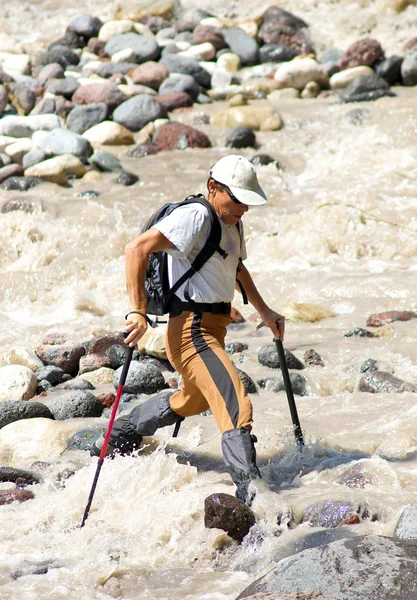 Tourist passes turbulent river. — Stock Photo, Image