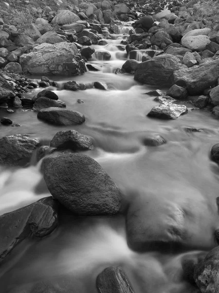 Przepływ rzeki szybki i ciemnych kamieni. — Zdjęcie stockowe