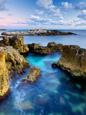 taş ve aralarında mavi deniz suyu.