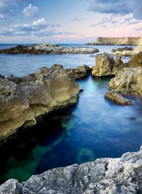 taş ve aralarında mavi deniz suyu.