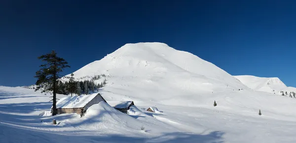 Casa y la cima de la montaña de nieve en el invierno . — Foto de Stock