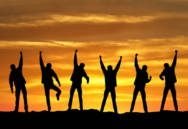 Silhouette of the team on sundown background.