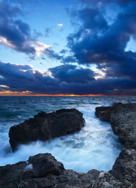 Deniz taş ve parlak gökyüzü gün batımı sırasında — Stok fotoğraf