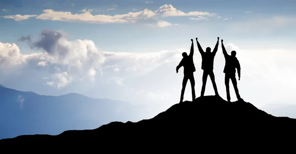 Silhouettes of a team on the mountain peak Stock Image