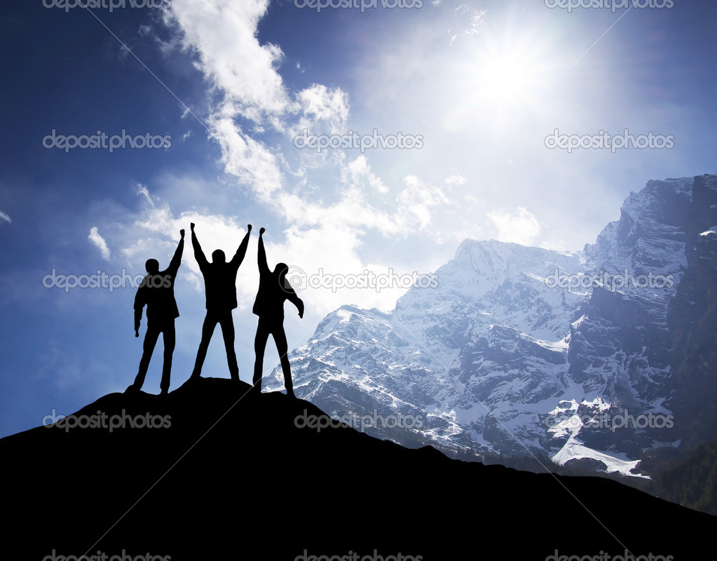 Silhouette of team on mountain peak