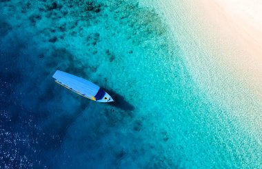 Tekne su yüzeyinde, yukarıdan görünüyor. Yukarıdan mavi su arka planı. Havadan gelen yaz deniz manzarası. Endonezya. 