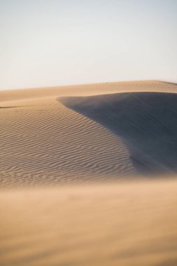 Gün batımında kum tepeleri ve güçlü rüzgar. Çölde yaz manzarası. Sıcak hava. Kumda çizgiler. 