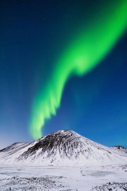 İzlanda 'da Aurora Borealis. Dağların üzerinden Kuzey Işıkları. Gökyüzünde parlak ışıklar olan bir kış gecesi manzarası. Kış zamanı kuzeyde manzara. Seyahat etmek için popüler bir yer.