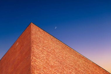 Gün batımında göksel bir eğime karşı bir bina. Arkaplan olarak gökyüzü renk gradyanı. Gün batımında gökyüzü ve ay. Doğa bileşimi.