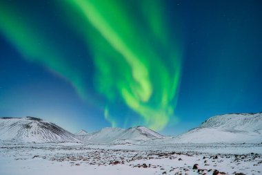 Aurora Borealis. Dağların üzerinden Kuzey Işıkları. Gökyüzünde parlak ışıklar olan bir kış gecesi manzarası. Kış zamanı kuzeyde manzara. Seyahat etmek için popüler bir yer.