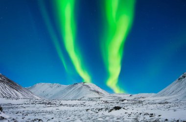 Doğa. İzlanda 'da Aurora Borealis. Dağların üzerinden Kuzey Işıkları. Gökyüzünde parlak ışıklar olan bir kış gecesi manzarası. Kışın kuzeyde manzara.. 