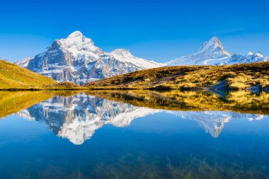 Yüksek dağlar ve gölün yüzeyindeki yansıma. Göllü Dağ Vadisi. Yaz aylarında dağlık arazide manzara. Fotoğraf yüksek çözünürlükte.