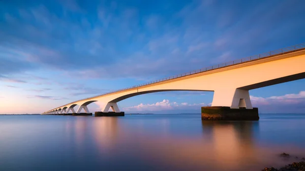 สะพานยาวข ามทะเลตอนพระอาท ายท บแสงยาว ในช วงพระอาท ตกท สดใส ทะเลและสะพาน สะพาน — ภาพถ่ายสต็อก