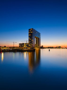 Amsterdam, Netherlands. A cityscape in the evening. A skyscraper and business center near the water in the bay. Architecture of the Netherlands. Travel photography.