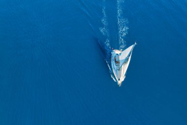 An aerial view of the sail yacht on the blue sea. Transparent clear water in the sea. Summer vacations and travels on a sailing yacht. Summer relaxation.